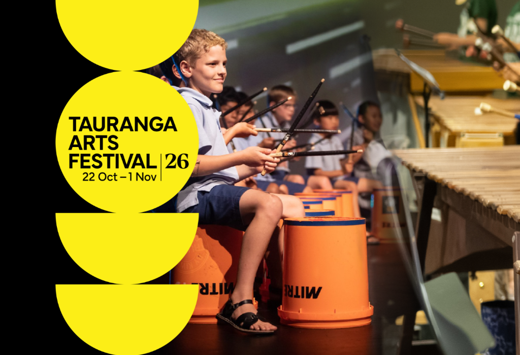 Tauranga Arts Festival 26 poster, 22 Oct–1 Nov. Children play bucket drums on a level stage floor. A boy in a blue shirt sits on an orange bucket. Yellow circular graphics on the left.