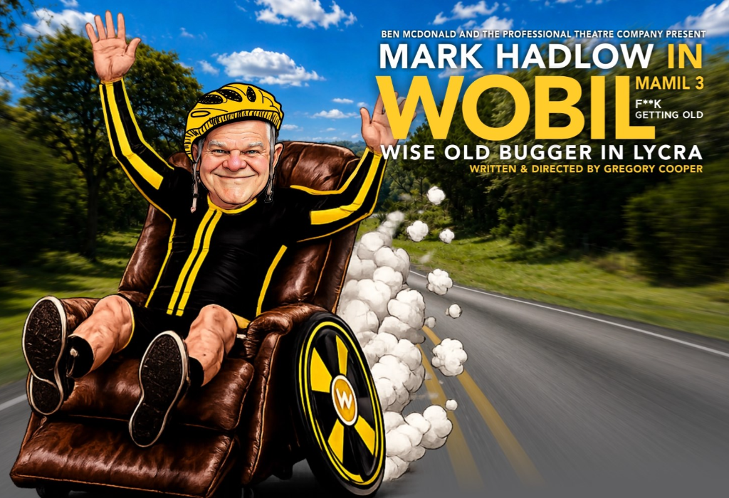 Mark Hadlow in yellow helmet and black lycra, seated in a brown leather recliner with large wheels. Speeding on a bitumen road with yellow centre lines. Text: WOBIL - WISE OLD BUGGER IN LYCRA.