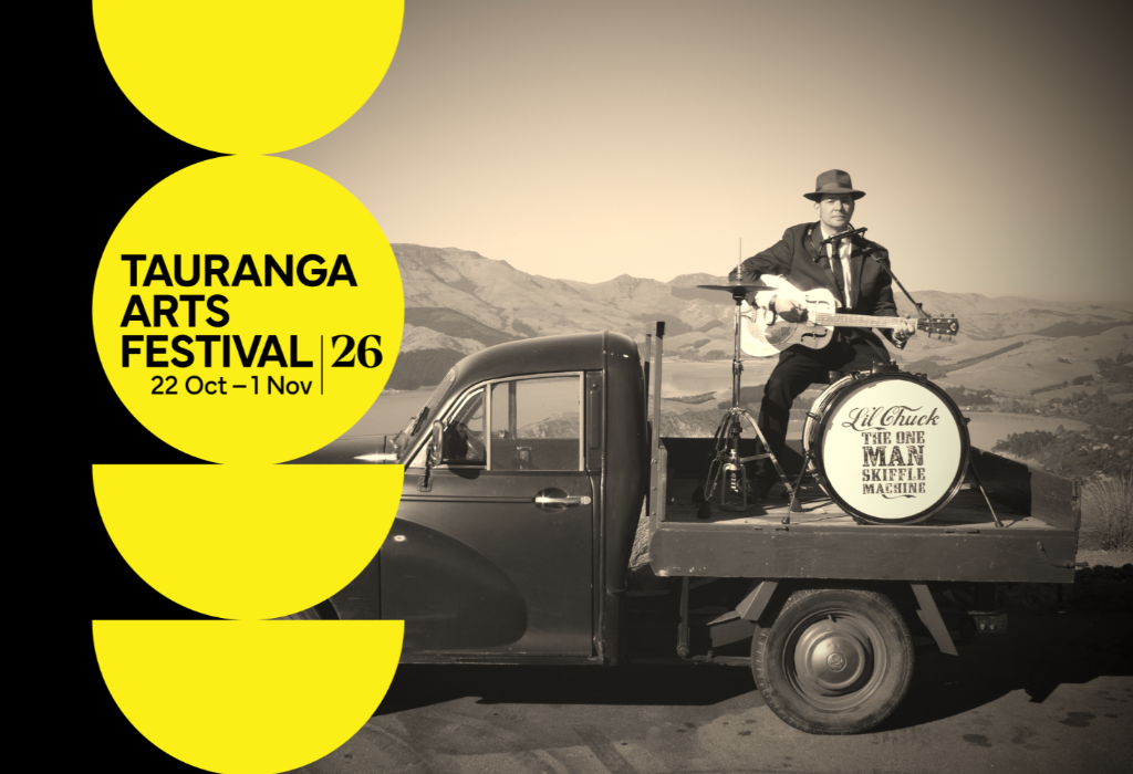 Tauranga Arts Festival 26, 22 Oct–1 Nov. Musician in a suit plays guitar and drums on a vintage truck tray. Hilly landscape background. Large yellow circles and semi-circles down the left side.