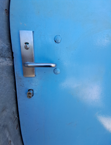 Bright blue door featuring a silver lever handle with a key lock, and a separate key cylinder below.